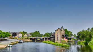 Picturesque view of Messac with a river weir and traditional town buildings lining the waterfront.