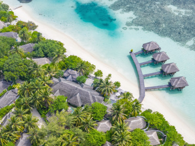 Aerial view of beautiful white sand beach, palm trees and villas, bungalows luxury beach scene of Maldives island