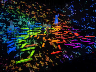 Person zwischen leuchtend bunten Schaukeln in der interaktiven Kunstinstallation teamLab Planets Tokyo