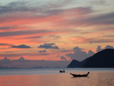 a sunset over a body of water with a mountain in the background