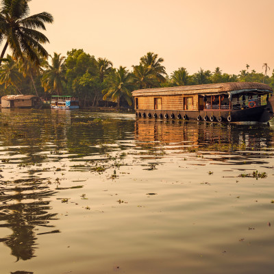 Goldene Abendstimmung mit Blick auf ein Hausboot in den Backwaters von Kerala