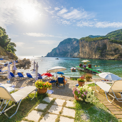 Sunbeds and umbrella on the beach in Corfu Island, Greece.