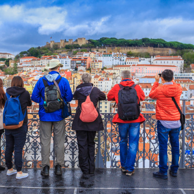 Group of tourists watching the cityscape of Lisbon and taking pictures of the castle architecture in Portugal