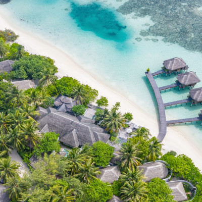 Aerial view of beautiful white sand beach, palm trees and villas, bungalows luxury beach scene of Maldives island