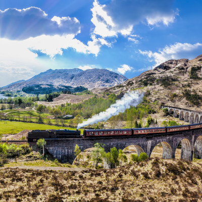 Glenfinnan Railway Viaduct in Scotland with the Jacobite steam train against sunset over lake