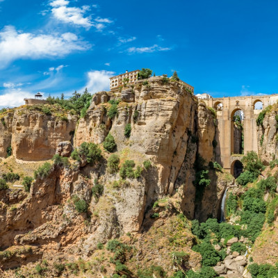 Tourists taking pictures to the Puente Nuevo bridge and the houses built on the edge of the cliff, in the ancient city of Ronda, Spain
