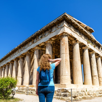 Greece Private Trip:Young woman looks at Temple of Hephaestus, Athens, Greece. This ancient Greek structure is one of main landmarks of Athens.
