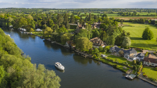 High-angle view of elegant riverside homes along the Thames, sought-after properties on the riverbank.