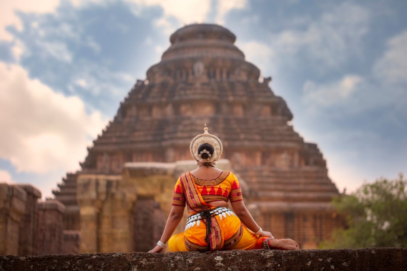 Odissi dancer pose in front of sun temple with sculptures in Konark odisha east India