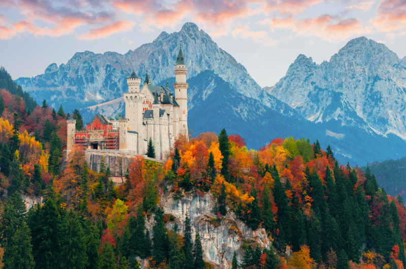 Picturesque autumn view on Neuschwanstein Castle with colorful trees and the Alps on background, Bavaria, Germany. Beautiful autumn colorful scenery.