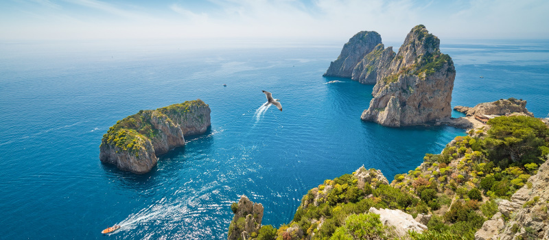 Enchanting Travels Italy Tours Aerial view of famous Faraglioni rocks from Capri island, Italy.