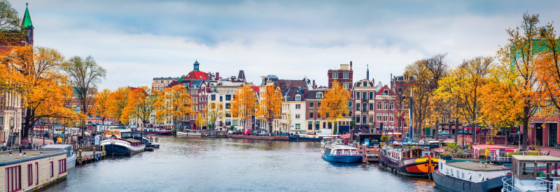 Panoramic autumn view of Amsterdam city. Famous Dutch channels and great cityscape. Gloomy morning scene of Netherlands, Europe. Traveling concept background. European Cities tours