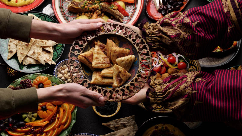 A,Woman,Passes,A,Plate,Of,Fried,Samosa