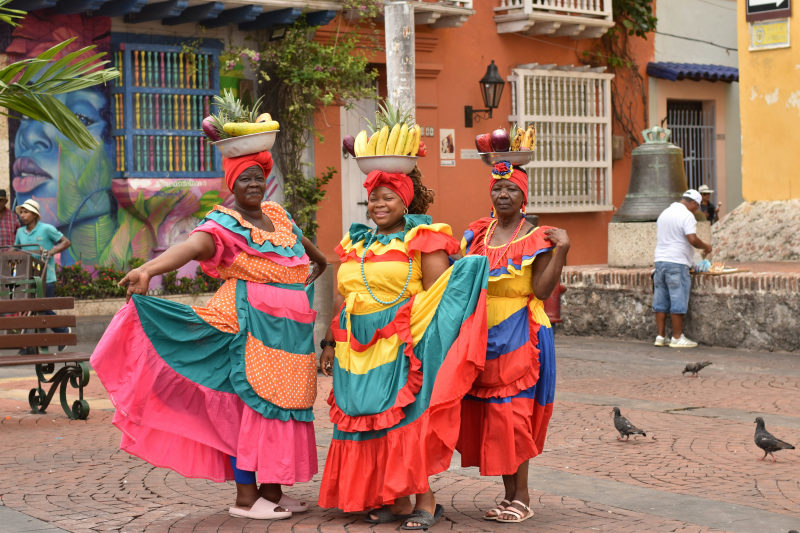 a-group-of-women-in-colorful-dresses-standing-next-to-each-other-colombia