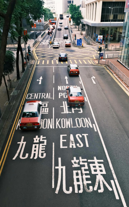 a city street with cars driving down it hong kong