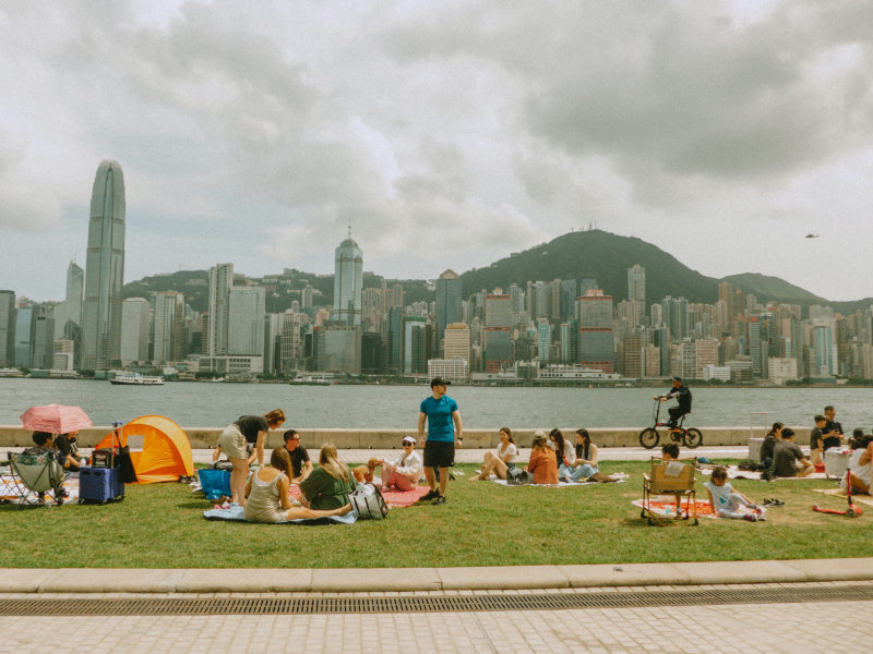 a group of people sitting on top of a lush green field hong kong
