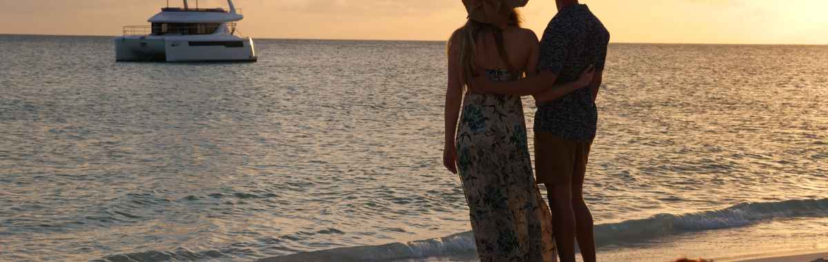 Couple looking out at a Moorings power catamaran in the sunset