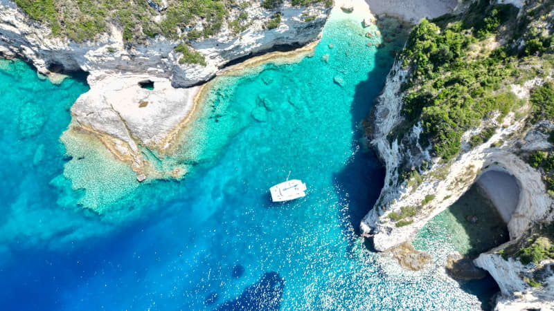 Birdseye view of yacht floating on the clear turquoise water in Corfu