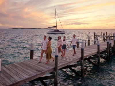 Friends walking along a dock with catamaran in the background