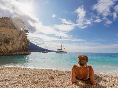 Frau liegt am Strand vor Sunsail Yachten