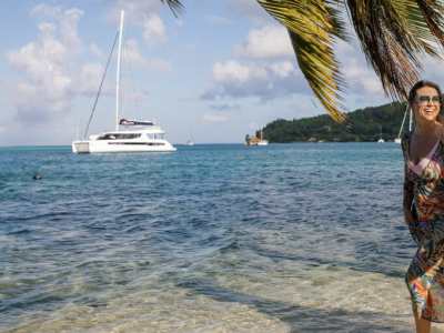 Couple walking on a beach in Tahiti with catamaran in the background