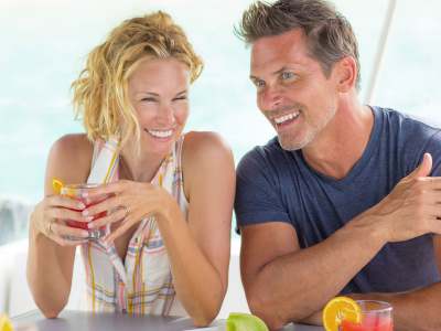 Happy couple drinking cocktails on a luxury crewed yacht