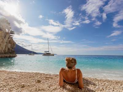 een vrouw ligt op het strand voor de Sunsail-jacht