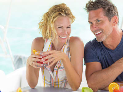 Happy couple drinking cocktails on a luxury crewed yacht