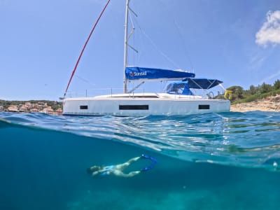 split image of a Sunsail yacht and person swimming below the ocean surface