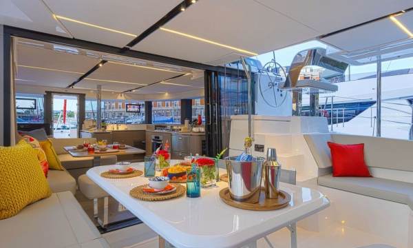 Moorings 4600 aft cockpit with a dining table and settees, opening to the saloon and galley beyond.