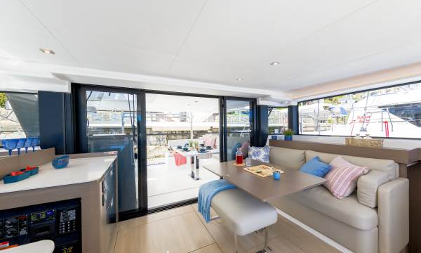 Moorings 4300 saloon with a settee and table, nav station to port, and sliding doors opening to the cockpit.