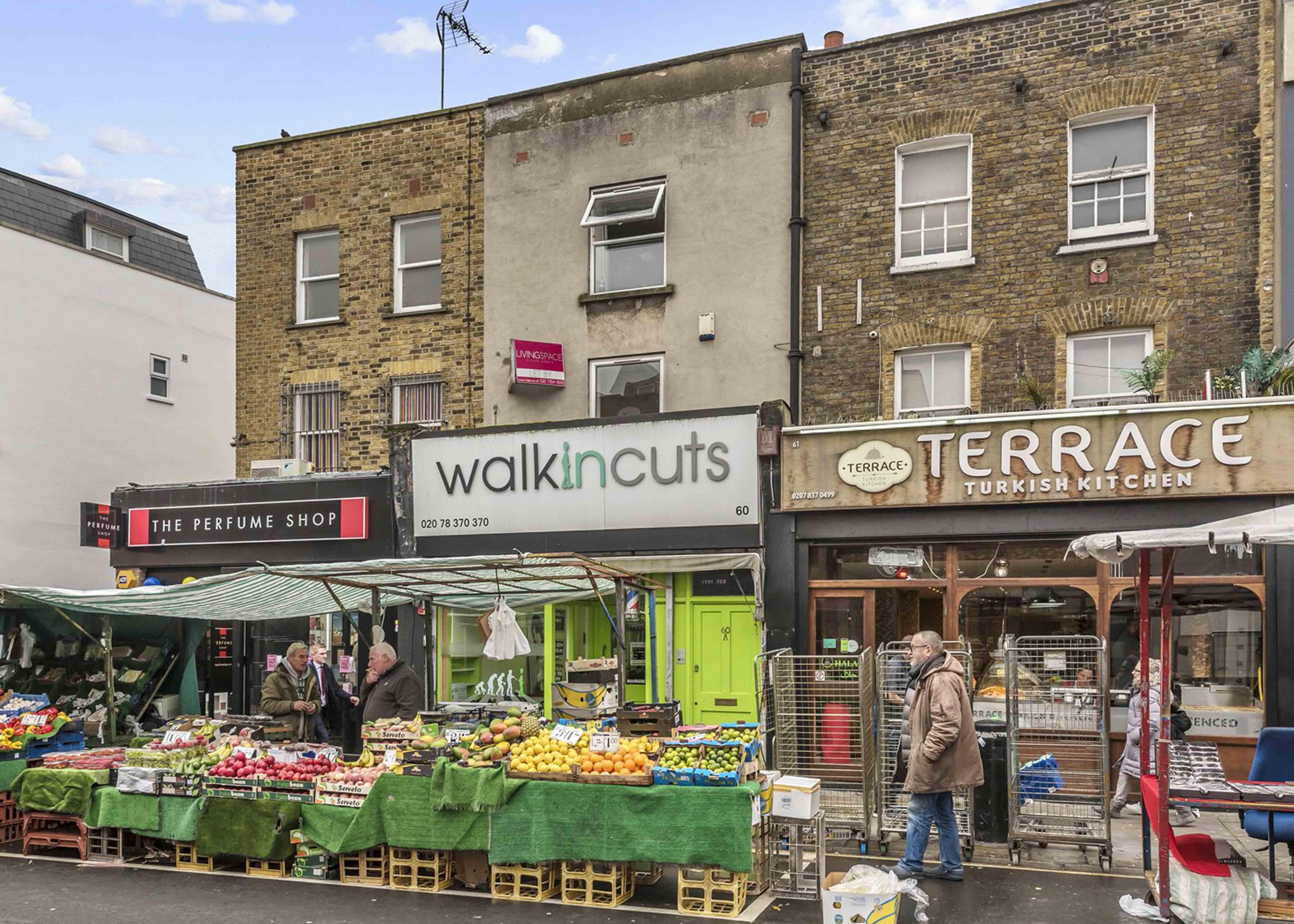 A fruit market with shops in the background