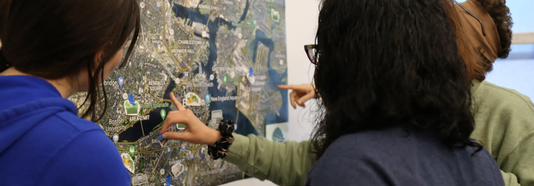 Students gathered around and pointing at a map on a wall