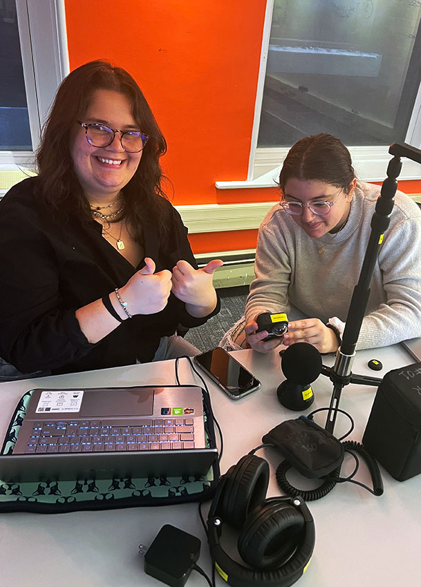 Two students, one looking at the camera and one working