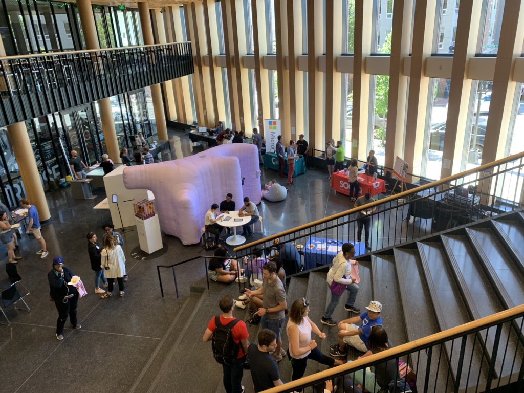 A number of people gathered around a purple inflatable at the base of stairs