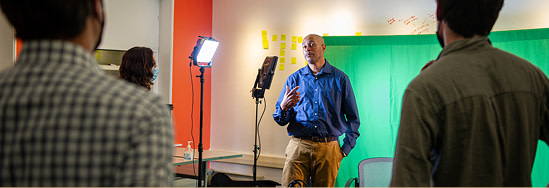 An individual in front of a green screen being interviewed