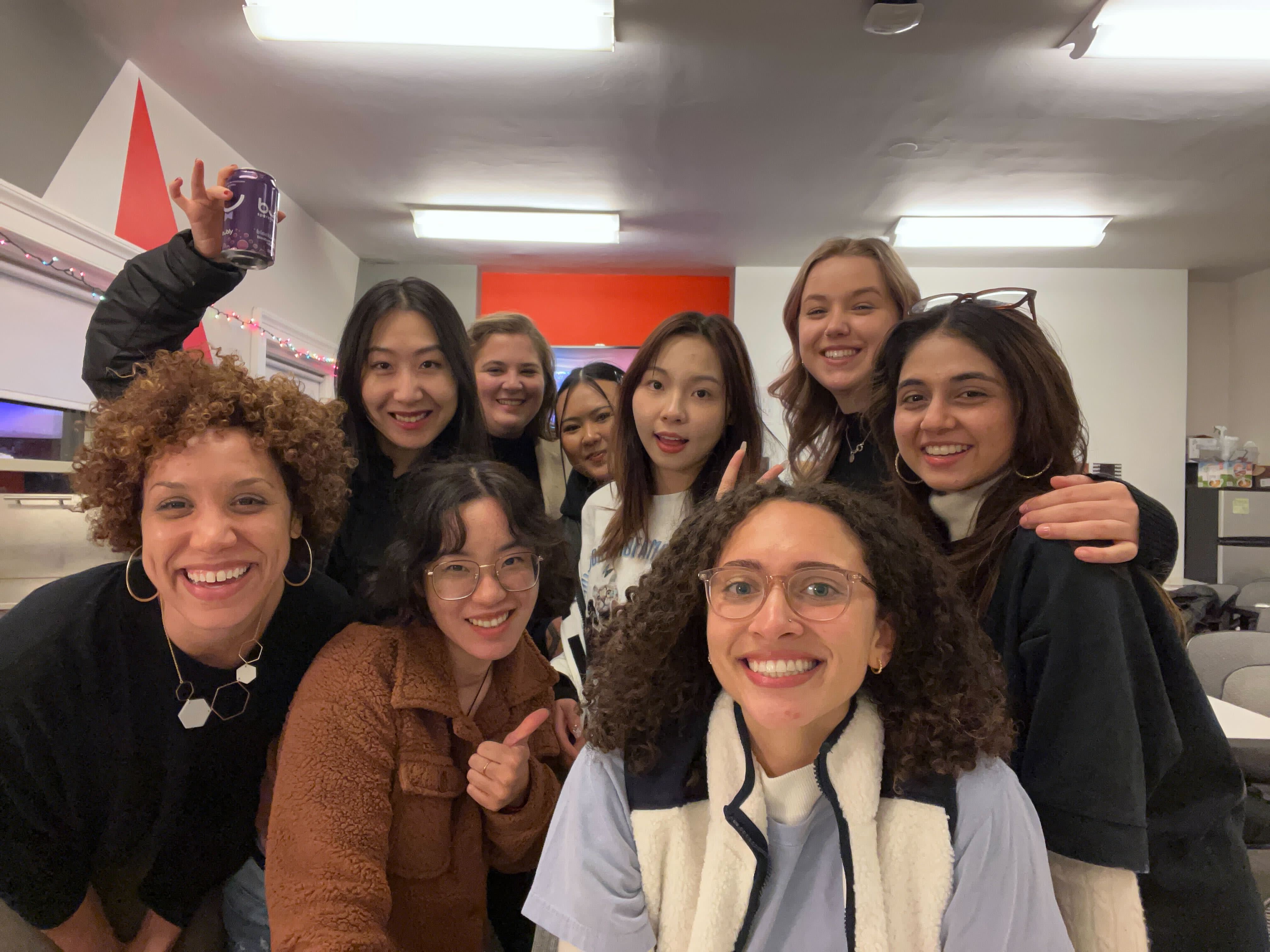 Nine individuals posing for a selfie at the Media Design studio art show