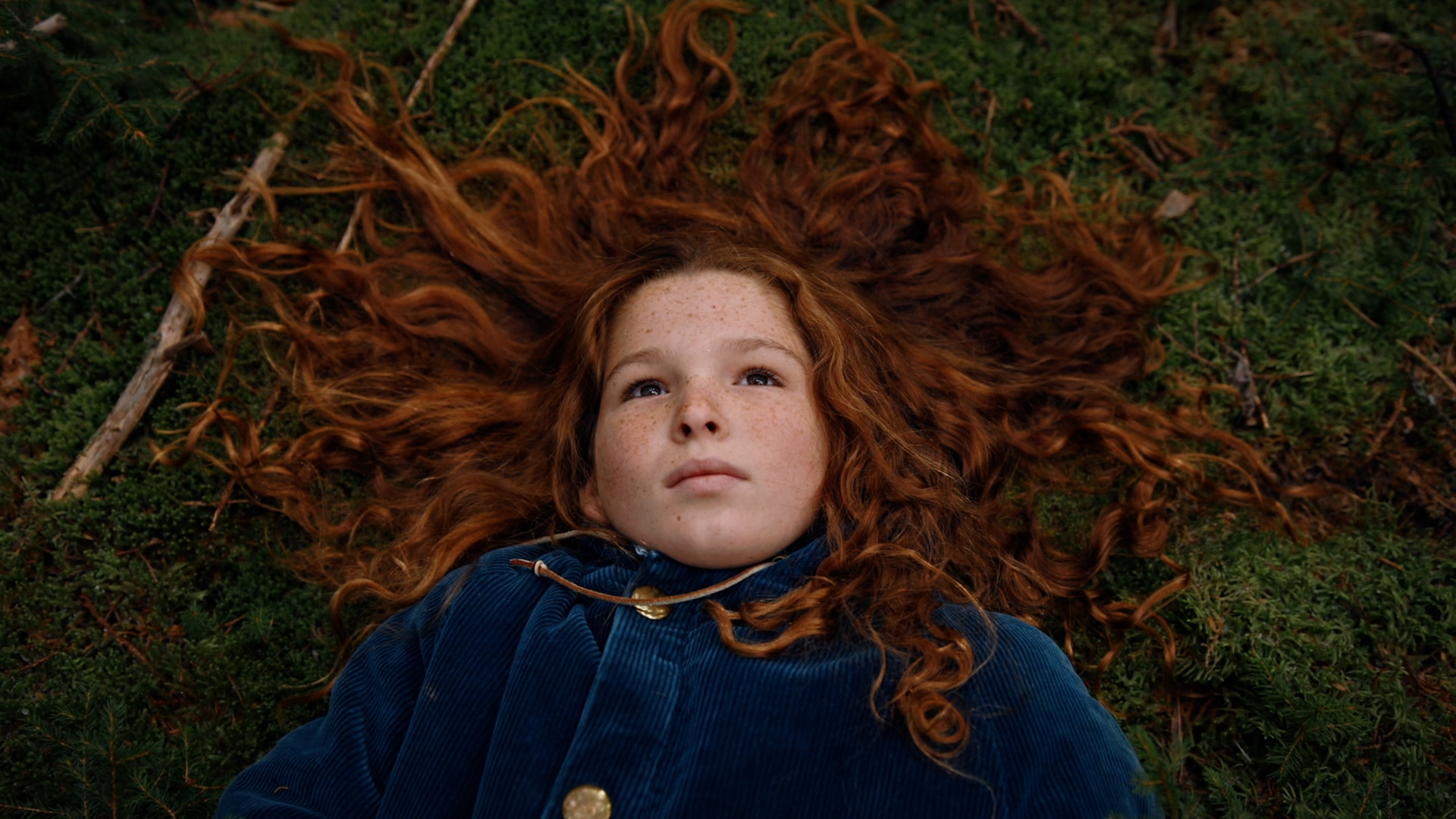 A still from the film King Coal, with a young girl with red hair laying on the grass