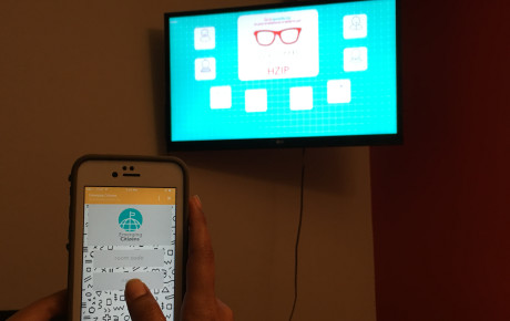 Person holding phone on the foreground and tv screen on the background 