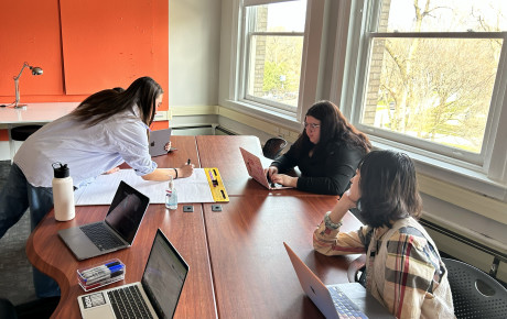 A number of individuals gathered around a table working on a project