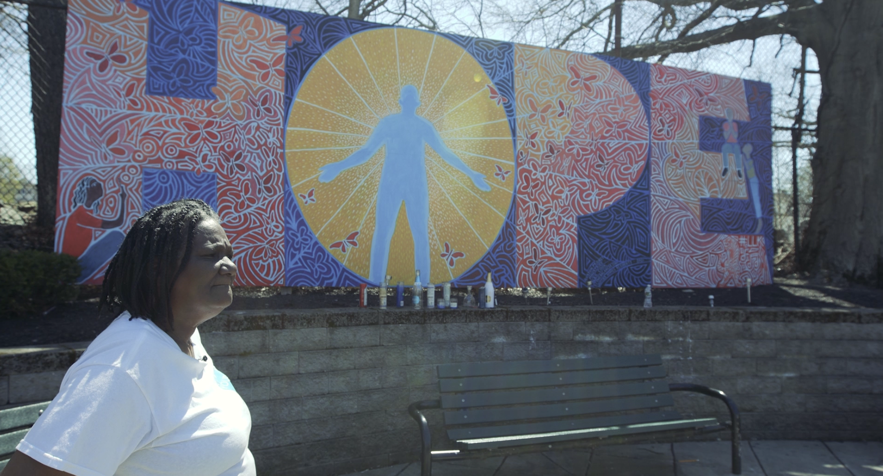 Norine Woods standing in front of a mural which reads "HOPE"