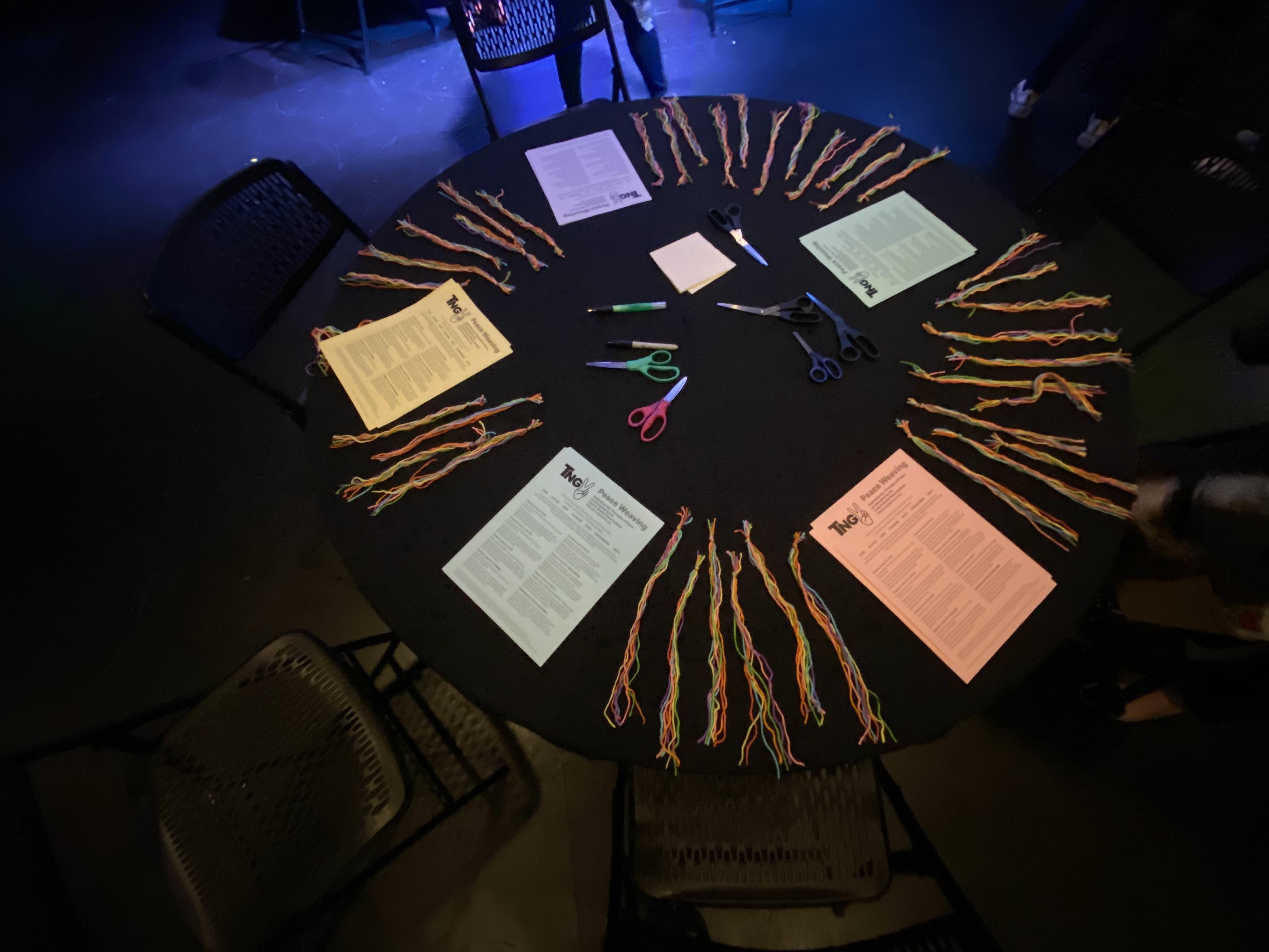 Peace weaving activities laid out on a black tablecloth with colorful string