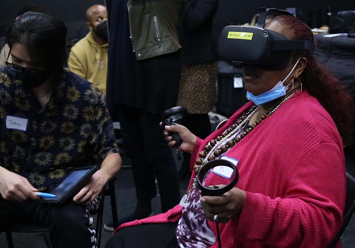 A person in a pink sweater wearing a VR headset and facemask