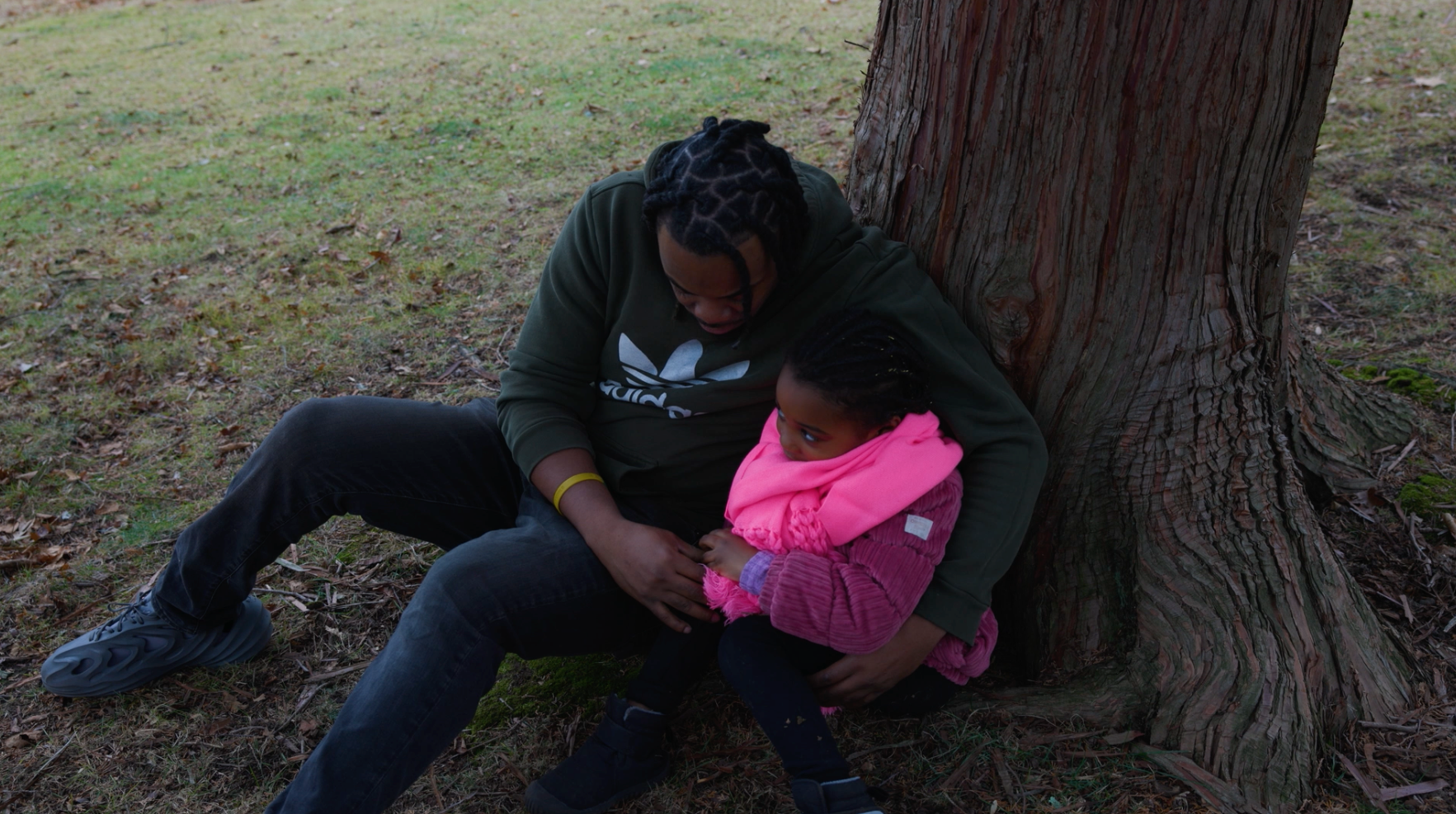 A father and daughter sitting beneath a tree