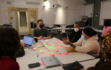 Studio participants brainstorming around a table with post-its