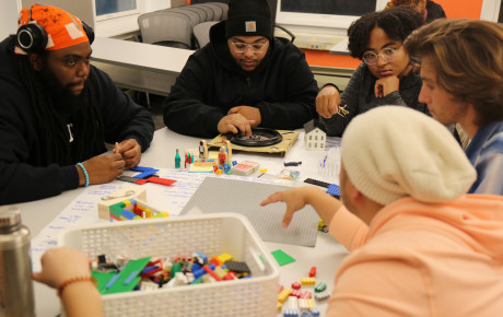 A number of individuals gathered around legos and other prototyping materials on a table