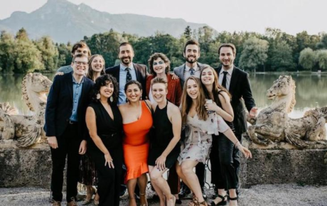 A crowd of students gathered in Salzburg, Austria with a beautiful mountain landscape behind them