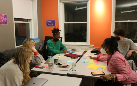 Five individuals brainstorming around a table with post-its