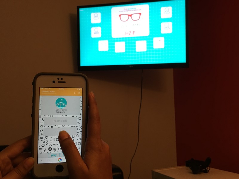 Person holding phone on the foreground and tv screen on the background 