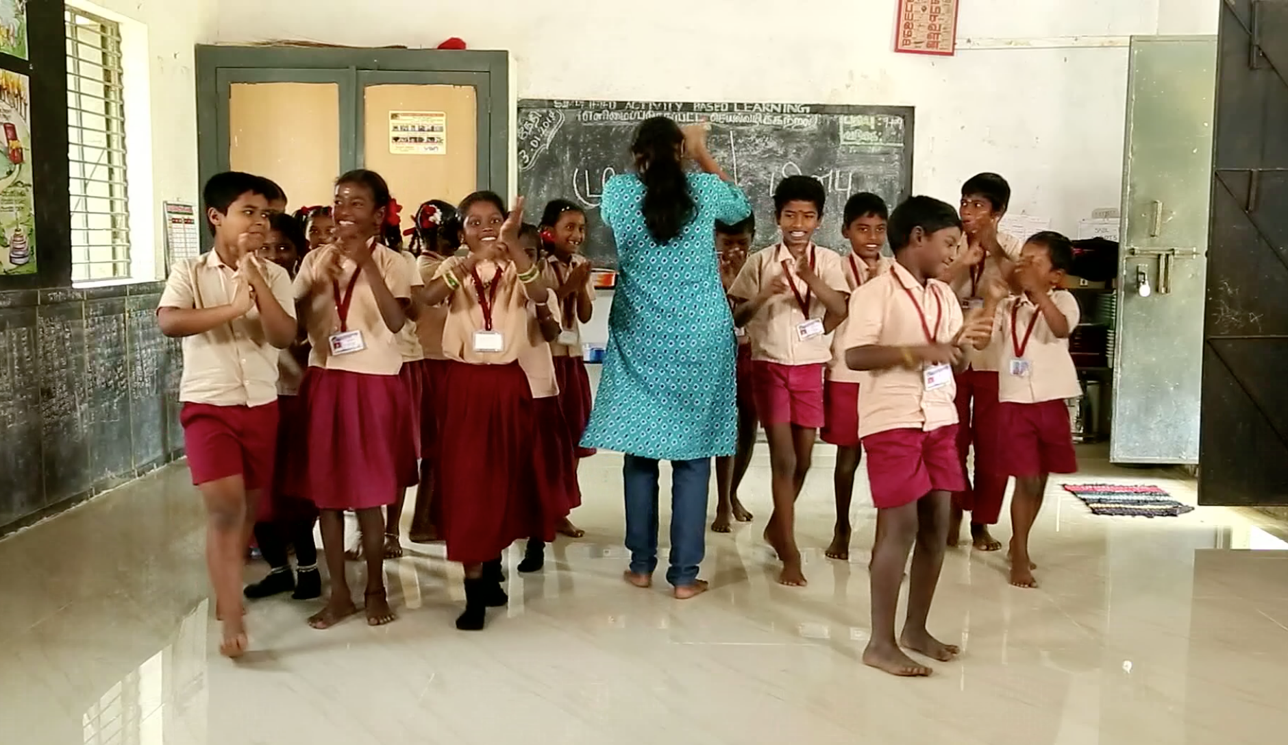 Children practice acting as rain during a mapping activity to show how water, flies, and surfaces spread diseases caused by open defecation.